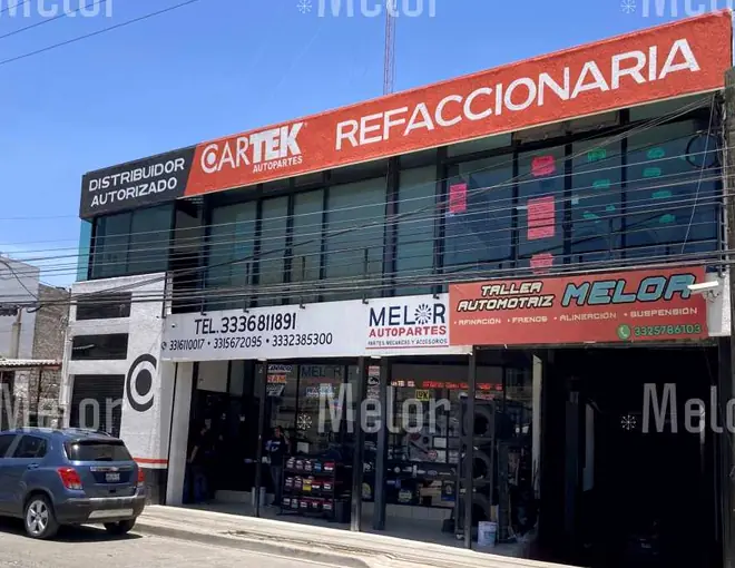 Melor Autopartes vista en ángulo desde la avenida, con el rótulo de refaccionaria arriba y el acceso del taller a la derecha